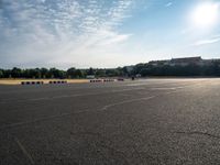 an empty parking lot filled with white, black and red stripes on the pavement with a city in the background