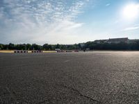 an empty parking lot filled with white, black and red stripes on the pavement with a city in the background