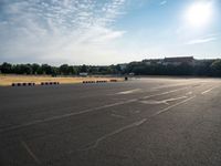 an empty parking lot filled with white, black and red stripes on the pavement with a city in the background