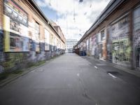 a blurry photo of an empty street with dump cans in between two buildings and trees