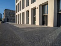 an empty sidewalk near buildings in a city area of europe, in front of blue sky