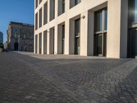 an empty sidewalk near buildings in a city area of europe, in front of blue sky