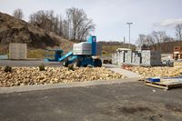 the blue trailer is parked by the pile of rocks in the parking lot behind the blue crane