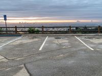 a photo of an empty parking lot and a city skyline from the distance, with clouds overhead