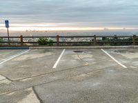 a photo of an empty parking lot and a city skyline from the distance, with clouds overhead