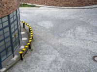 black and yellow striped barriers line the road next to brick buildings on a gray cloudy day