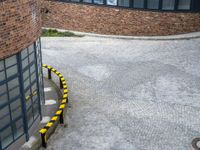 black and yellow striped barriers line the road next to brick buildings on a gray cloudy day