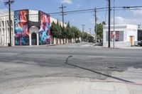 the intersection in an urban setting with a building and street art on the corner,