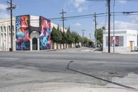 the intersection in an urban setting with a building and street art on the corner,