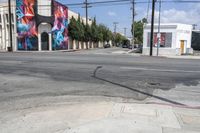 the intersection in an urban setting with a building and street art on the corner,