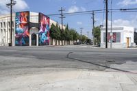 the intersection in an urban setting with a building and street art on the corner,