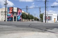 the intersection in an urban setting with a building and street art on the corner,