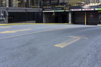 a skateboard sitting on top of an empty parking lot near some tall buildings and yellow lines