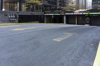 a skateboard sitting on top of an empty parking lot near some tall buildings and yellow lines