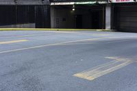 a skateboard sitting on top of an empty parking lot near some tall buildings and yellow lines