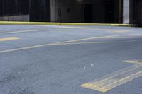 a skateboard sitting on top of an empty parking lot near some tall buildings and yellow lines