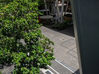 several vehicles are parked under an awning beside a walkway and tree filled sidewalk in the city