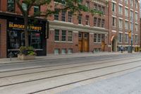 two mopeds and one bicycle parked in front of an old brick building and a railroad crossing