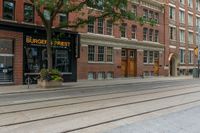 two mopeds and one bicycle parked in front of an old brick building and a railroad crossing