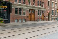 two mopeds and one bicycle parked in front of an old brick building and a railroad crossing