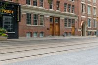 two mopeds and one bicycle parked in front of an old brick building and a railroad crossing