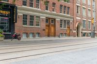 two mopeds and one bicycle parked in front of an old brick building and a railroad crossing