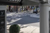 a man is walking down the street, passing by some bushes and a traffic light