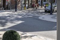 a man is walking down the street, passing by some bushes and a traffic light