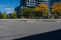 a fire hydrant sitting in front of two tall buildings with trees surrounding it with yellow paint on the pavement