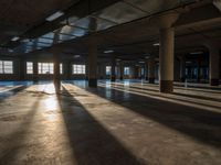 an empty room filled with lots of windows and chairs on the concrete floor with sunlight coming through windows