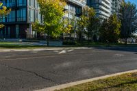 a red car drives past two large modern buildings in the background, with autumn trees