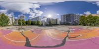 a skateboarder jumping his board at the skate park outside in daylight time with clouds and trees