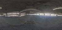 an indoor skateboard park is under construction with concrete walls and exposed beams above and below the ramp