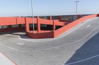 a skateboarder performs tricks on a surface in an empty parking lot near an overhead wall