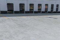 a man is riding a skateboard by an empty building on the road by some electrical wires