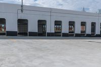 a man is riding a skateboard by an empty building on the road by some electrical wires