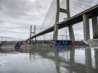 this is an urban skate park with graffiti painted on it's concrete ground and a bridge in the background