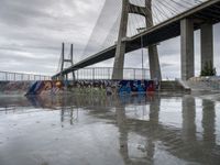 this is an urban skate park with graffiti painted on it's concrete ground and a bridge in the background