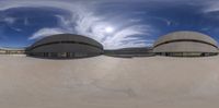 an empty skateboard court has round concrete roofs and a big dome like structure at one end