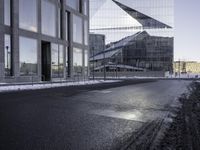 a person skates past a large glass building in the distance between two other buildings