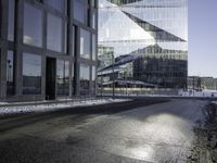 a person skates past a large glass building in the distance between two other buildings