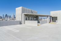 the large parking garage is situated below an urban skyline, which features high - rise concrete walls