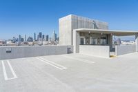 the large parking garage is situated below an urban skyline, which features high - rise concrete walls