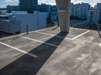 the shadow of a building from a concrete parking garage in front of tall buildings and a blue sky