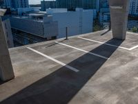 the shadow of a building from a concrete parking garage in front of tall buildings and a blue sky