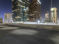 a night scene showing a building and some cars going down a highway next to tall buildings