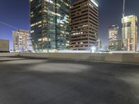 a night scene showing a building and some cars going down a highway next to tall buildings