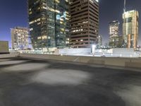 a night scene showing a building and some cars going down a highway next to tall buildings