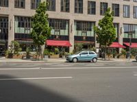 the car is parked on the side of the street beside the store's canopy