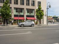 the car is parked on the side of the street beside the store's canopy